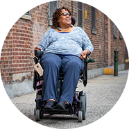 Happy woman riding down an urban sidewalk in her power chair.