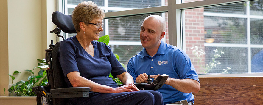 A NSM technician helping an elderly woman get familiar with her new power chair.