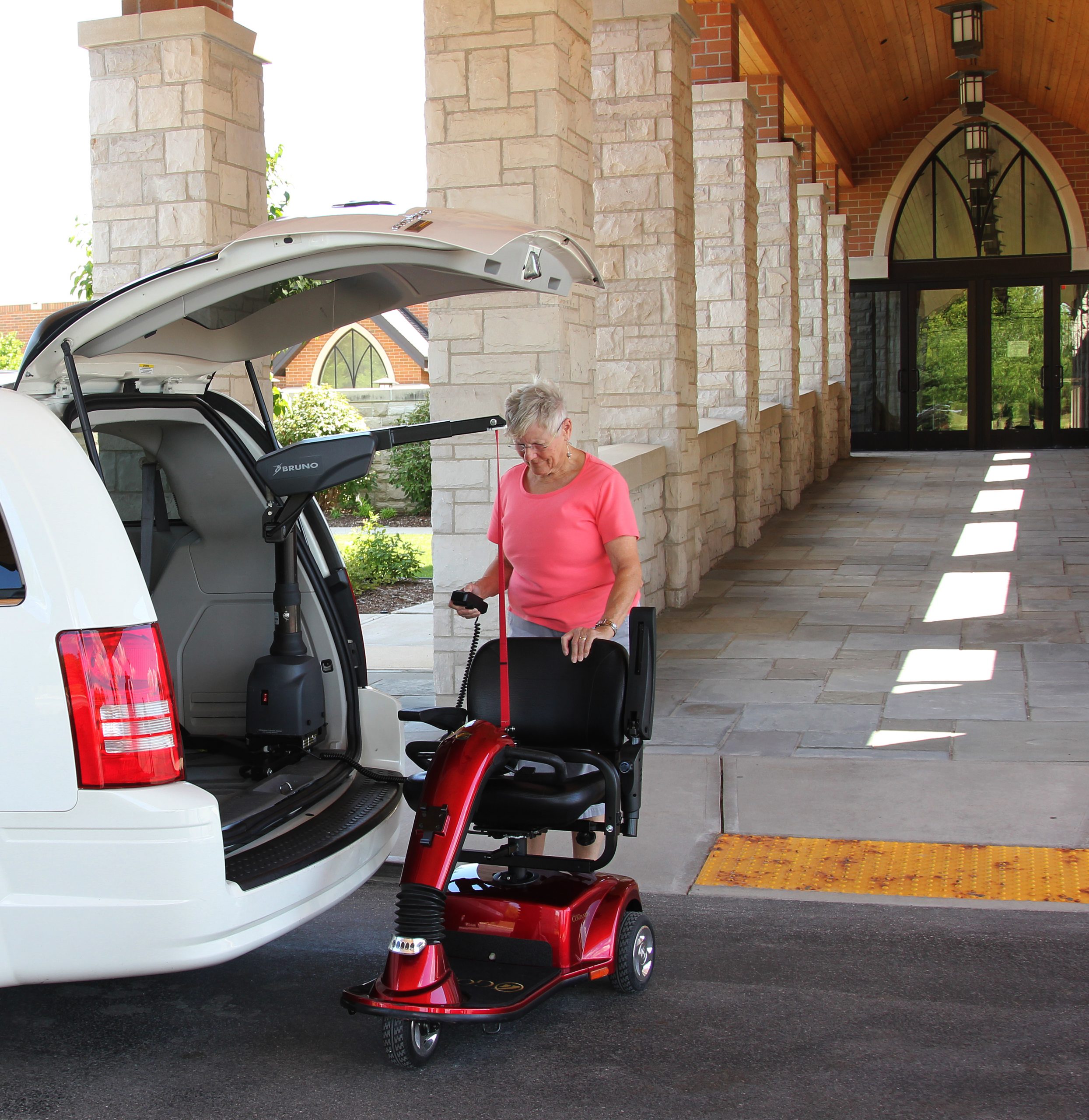 A woman putting a scooter into a van with a curb sider
