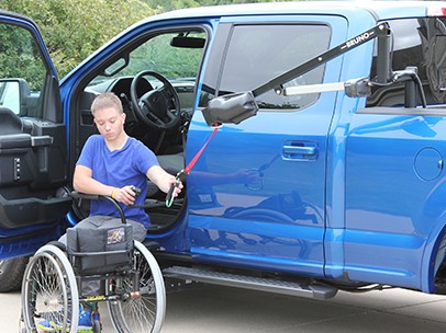 A man attaching a Lift to his scooter by a truck