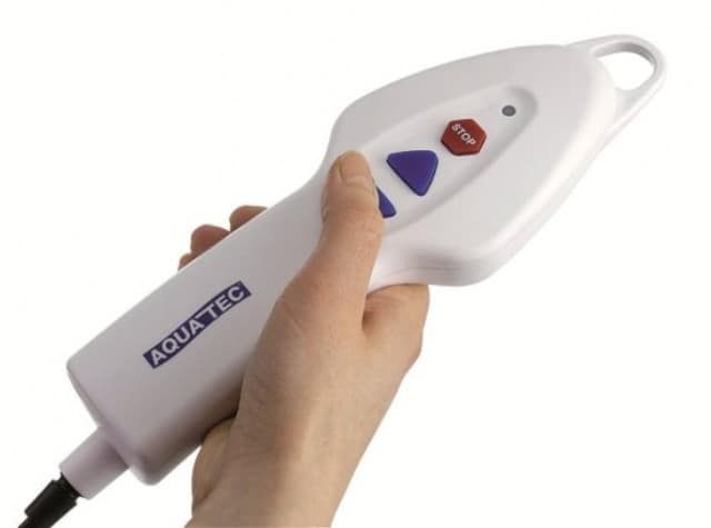 A hand holding a remote to a bath lift