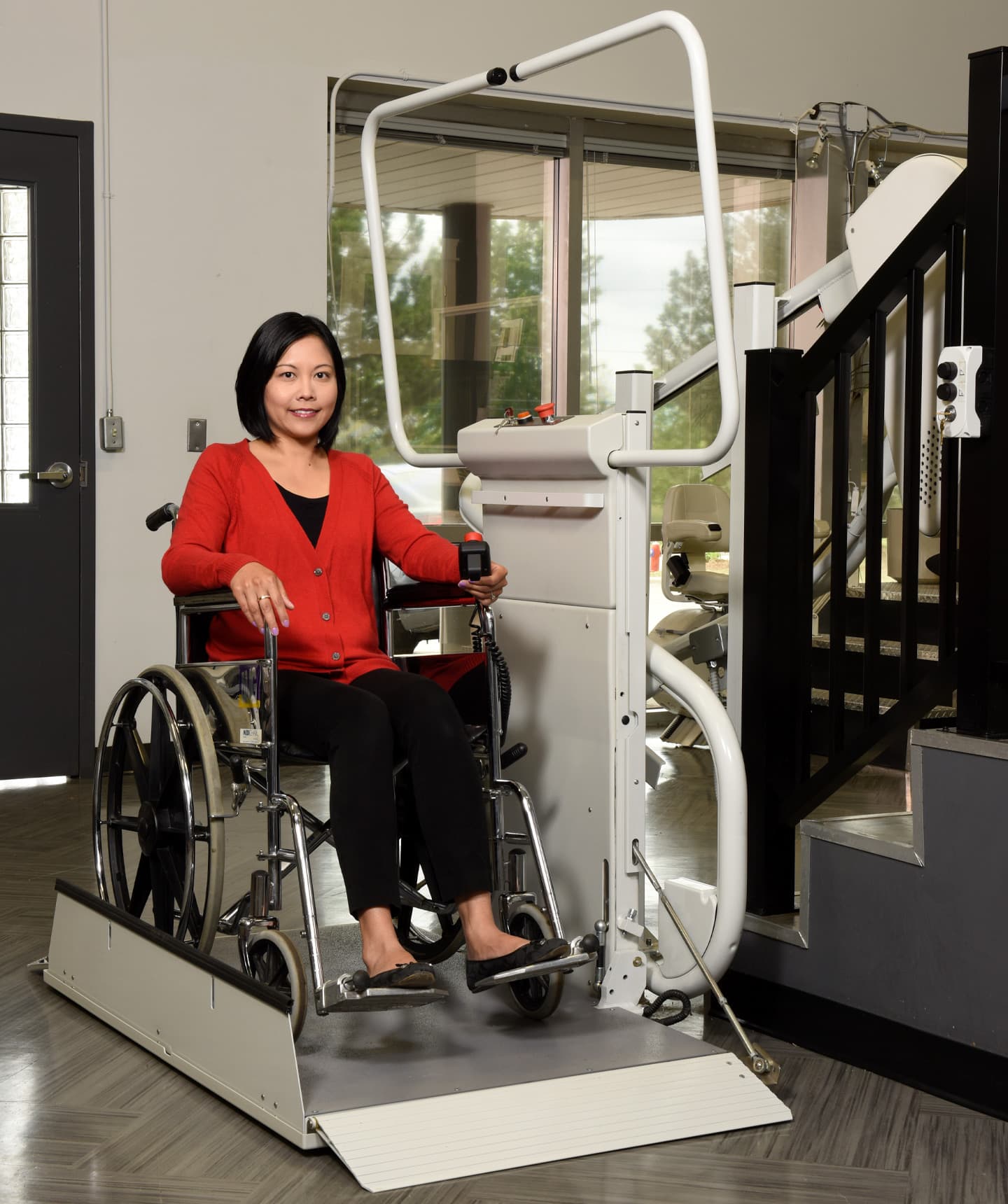 A woman in a wheelchair using a platform lift on stairs