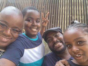 A cheerful group selfie featuring four people, smiling and posing together outdoors.